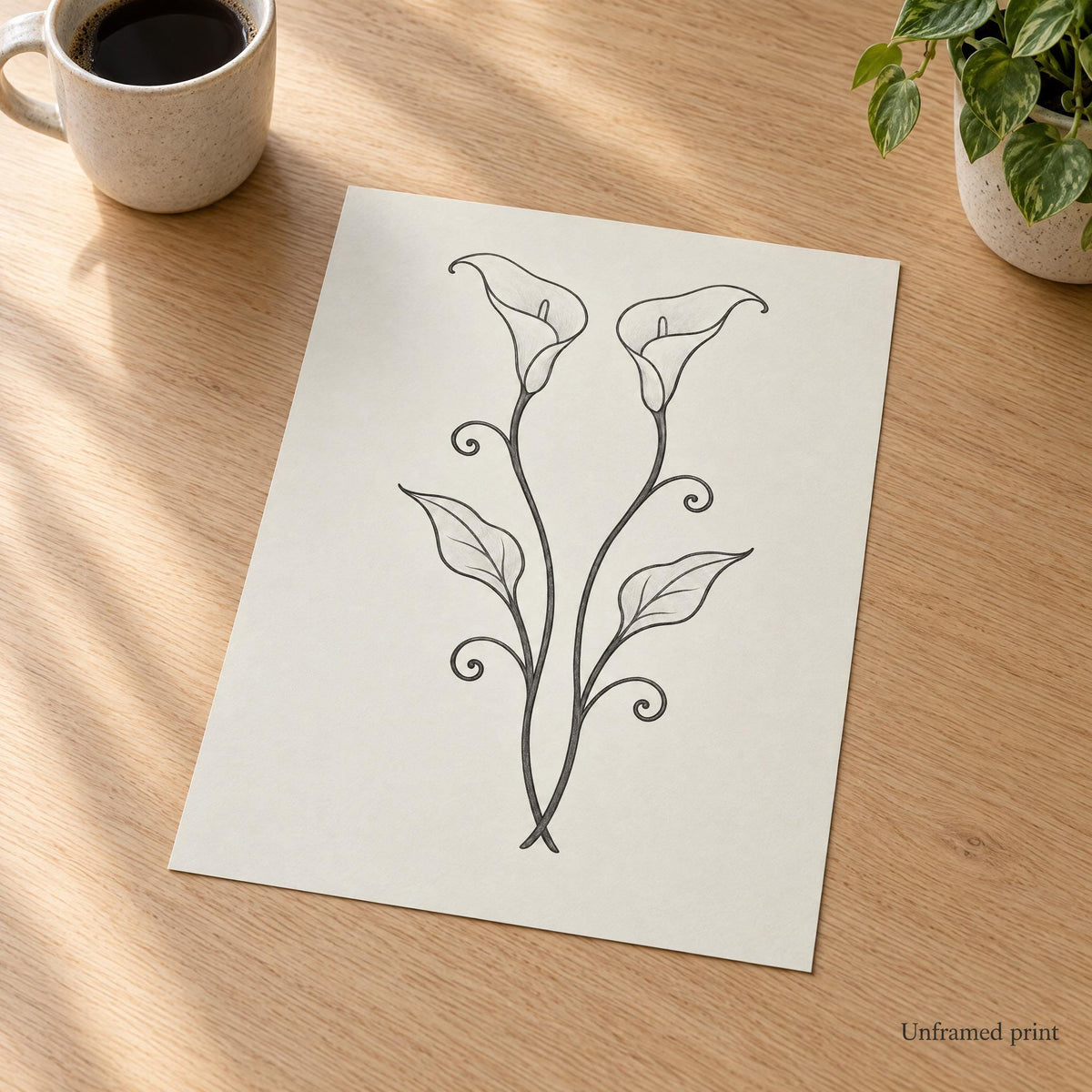 Unframed calla lily art print lying flat on an oak desk, shown without a frame