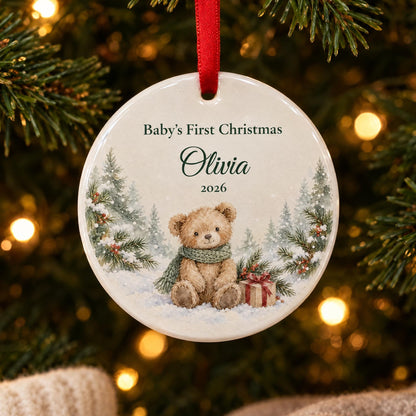 Baby's first Christmas ornament with a watercolor teddy bear and the name Olivia, hanging on a lit Christmas tree