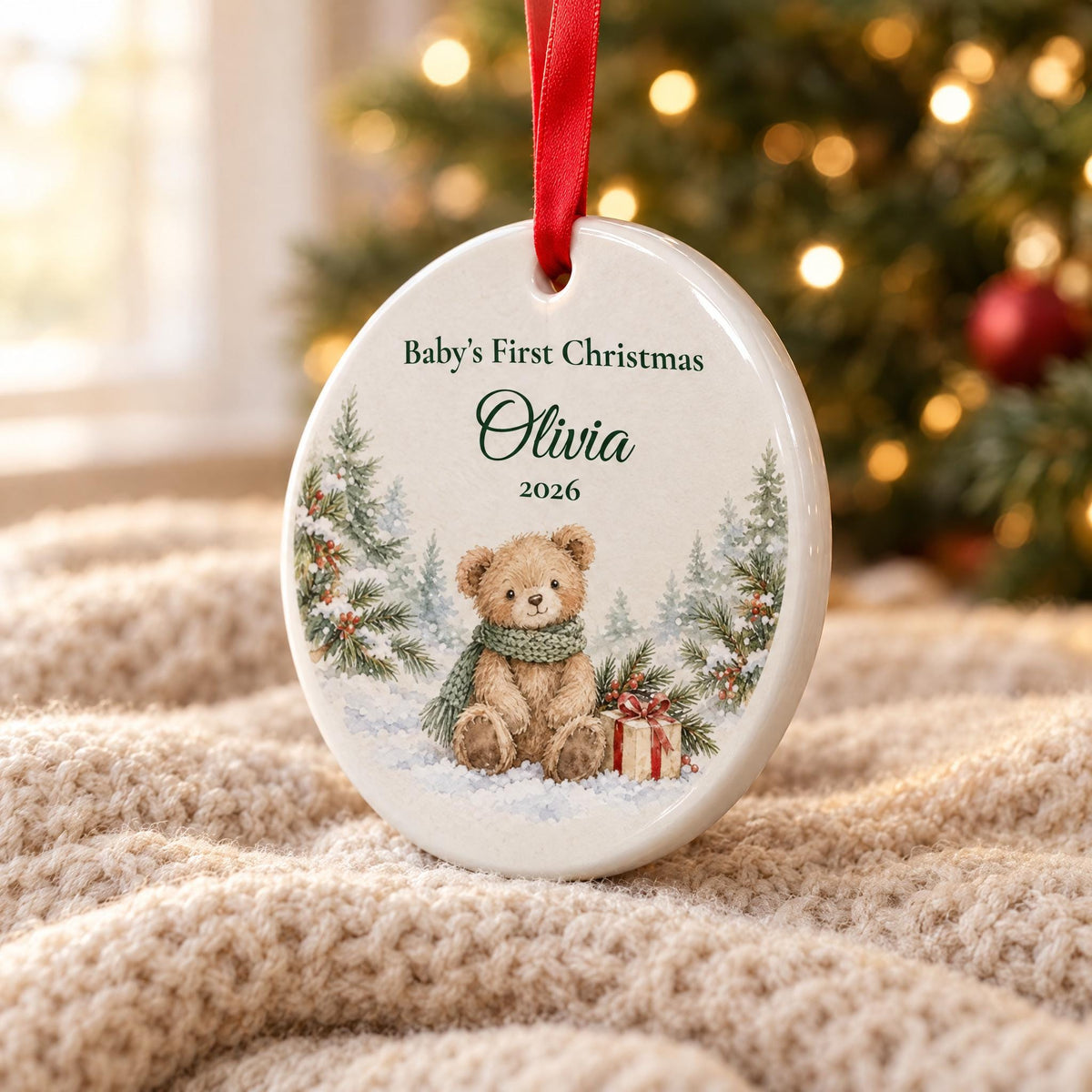 Close-up of the glossy white ceramic edge, red ribbon and printed teddy bear on the baby's first Christmas ornament