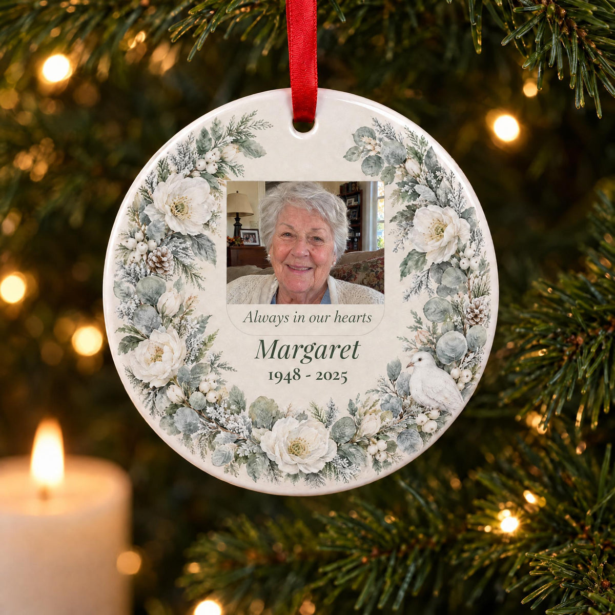Memorial photo ornament with a watercolor winter wreath, a photo, name and years, on a Christmas tree by a candle