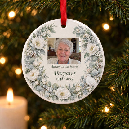 Memorial photo ornament with a watercolor winter wreath, a photo, name and years, on a Christmas tree by a candle