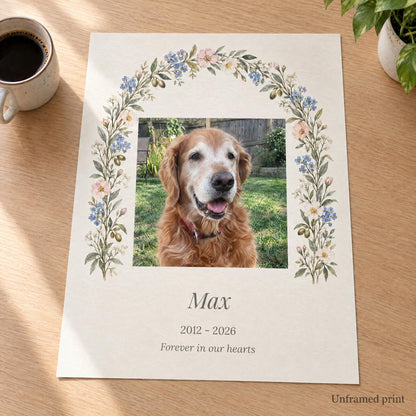 Unframed pet memorial art print with a dog photo and name lying flat on a wooden desk, shown without a frame