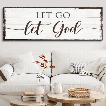 Long white plank-look canvas sign with a worn dark border, LET GO above let God in brown script, over a white sofa