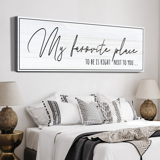 My Favorite Place to Be Is Right Next to You canvas sign in thin black handwriting on white, above a bed