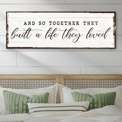 And So Together They Built a Life They Loved canvas sign in black lettering on white, above a bed with green pillows