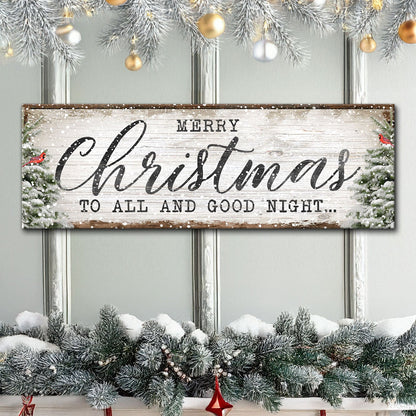Long Merry Christmas canvas sign in charcoal script with snowy pines at both ends and a red cardinal, above a garland