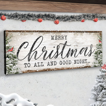 Merry Christmas Good Night Snowy Pines canvas in an angled close-up on a white wall under red-bauble tinsel
