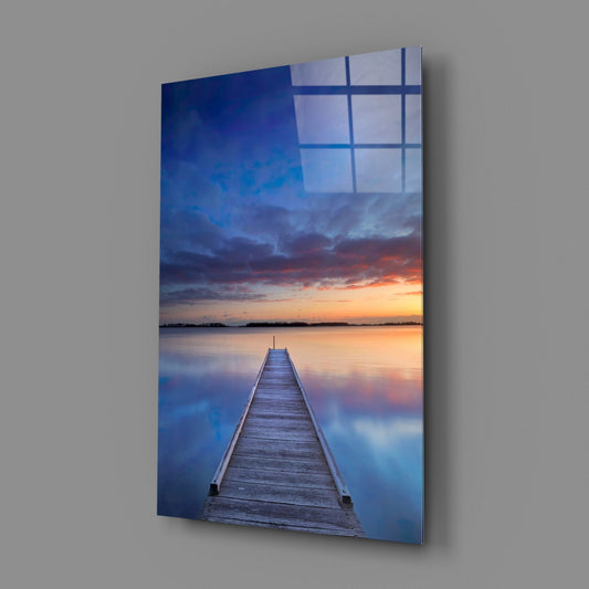 Twilight pier vertical glass wall art on a gray wall with a window reflected in the glossy surface