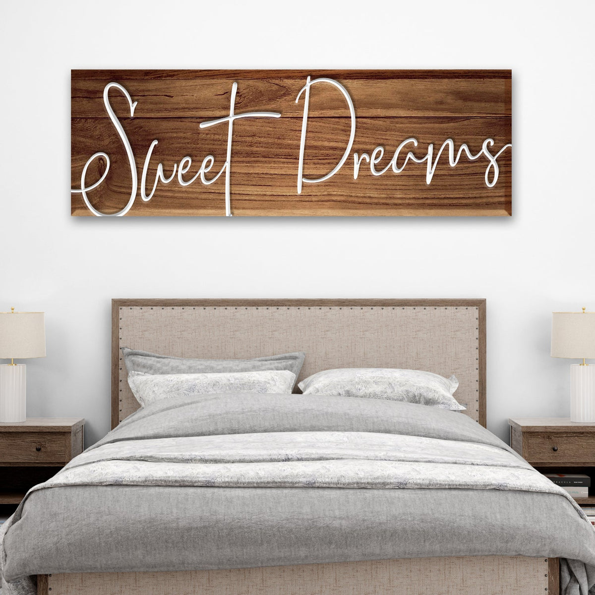 Sweet Dreams canvas sign in white script on a brown wood-look background, hung above a gray upholstered bed