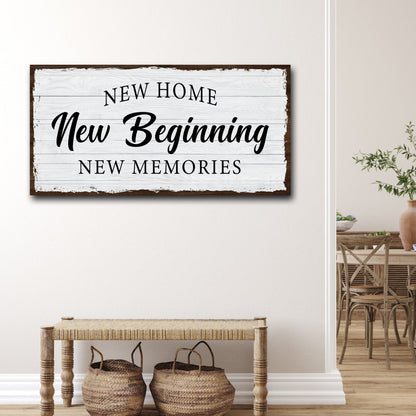 White wood-look canvas sign with a dark worn edge reading New Home, New Beginning, above a woven bench with baskets