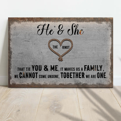 He and She canvas sign with a rope heart and a couple quote on gray, leaning against a white wall on a wood floor