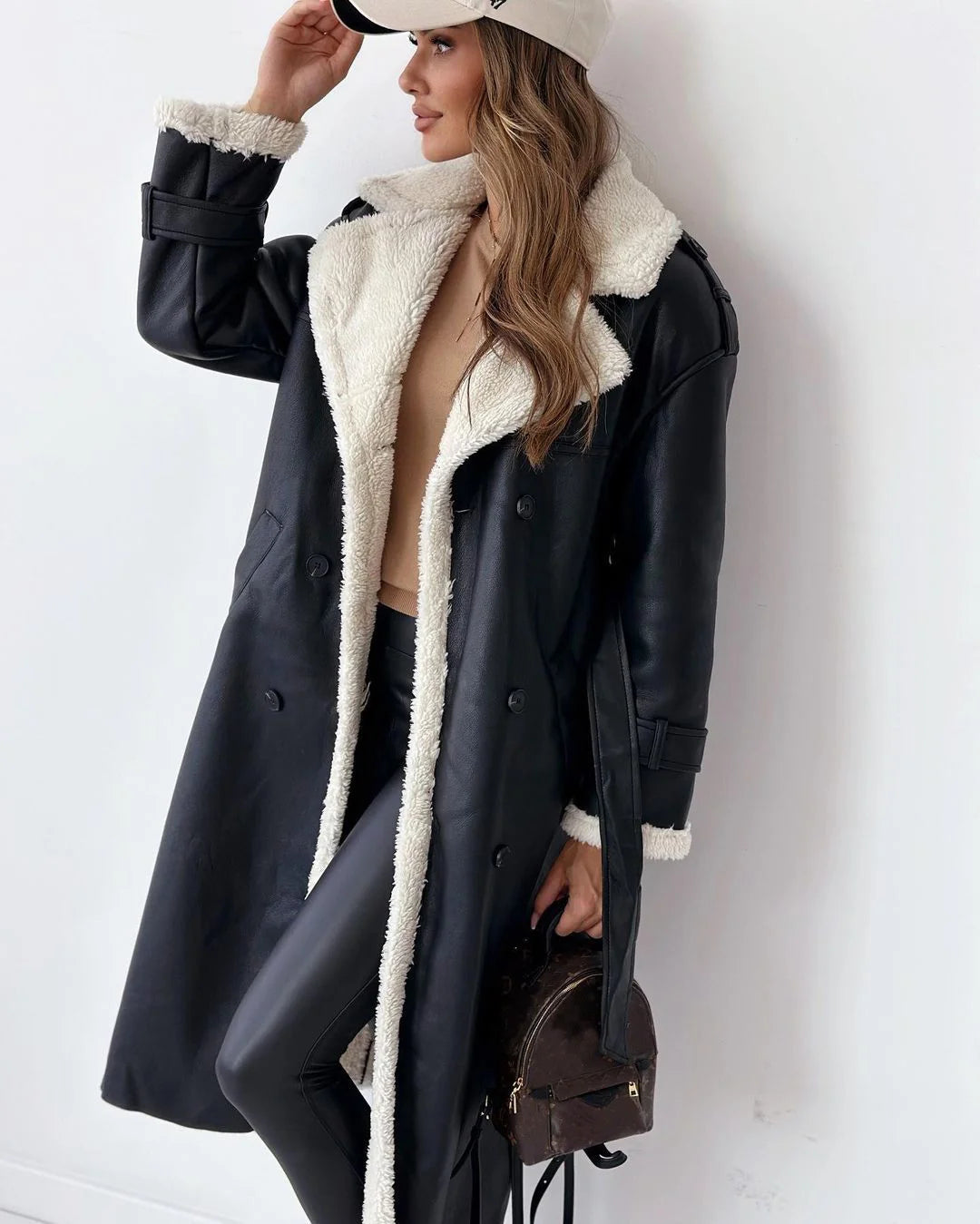 woman wearing black faux leather coat with white shearling lining
