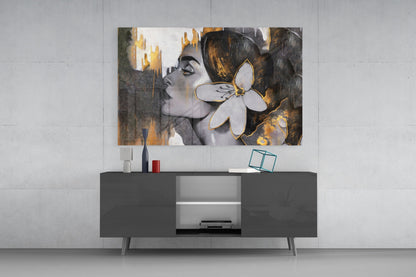 Woman with a white lily in gold and gray glass wall art above a gray sideboard with a red lamp on a concrete wall