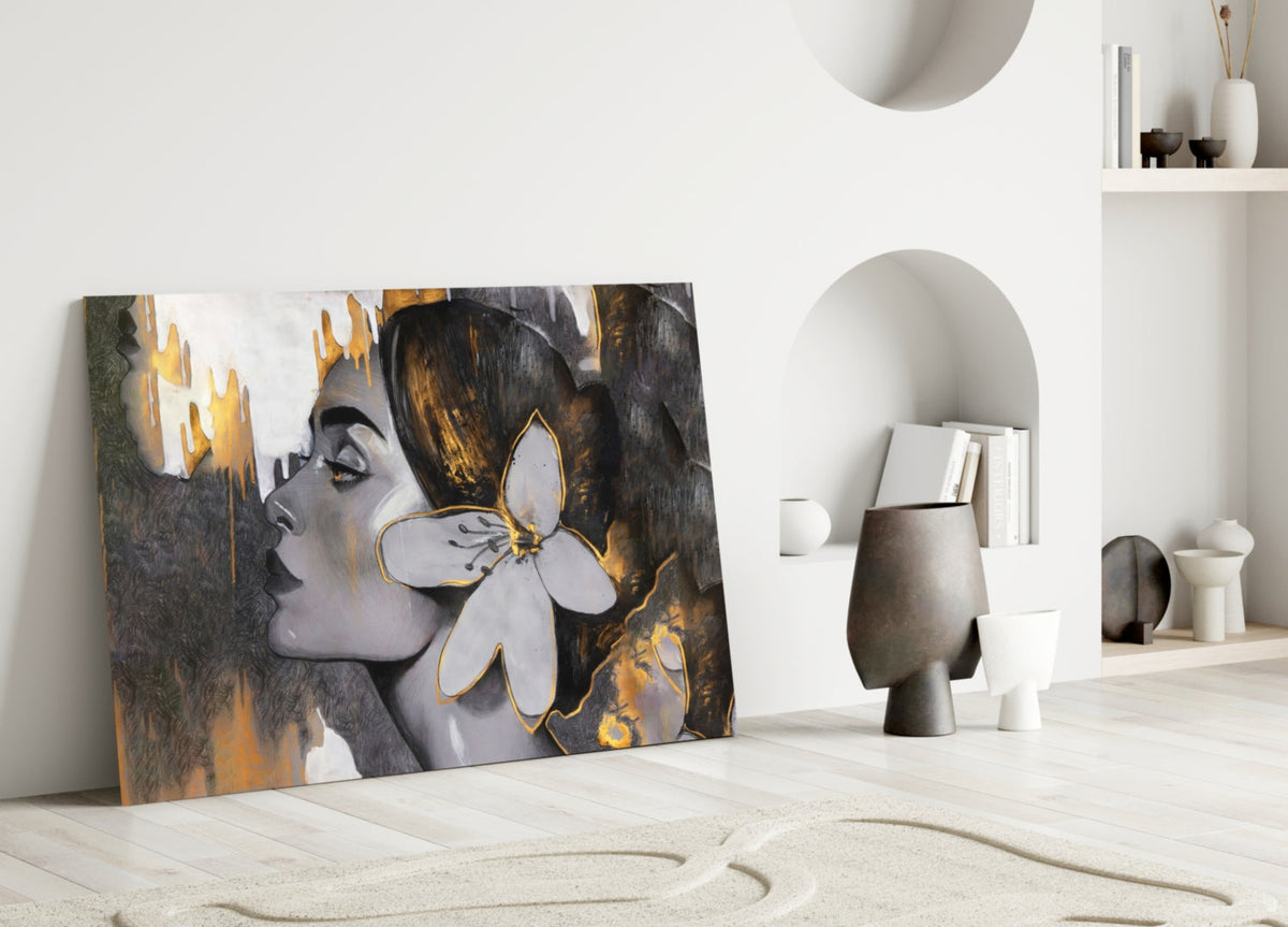 Woman with a white lily in gold and gray glass wall art leaning against a white wall beside an arched alcove