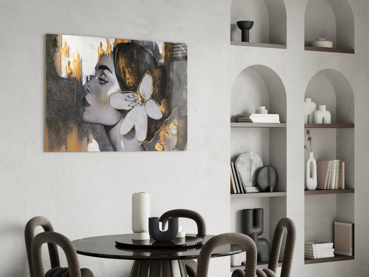 Woman with a white lily in gold and gray glass wall art above a round dining table beside arched shelves