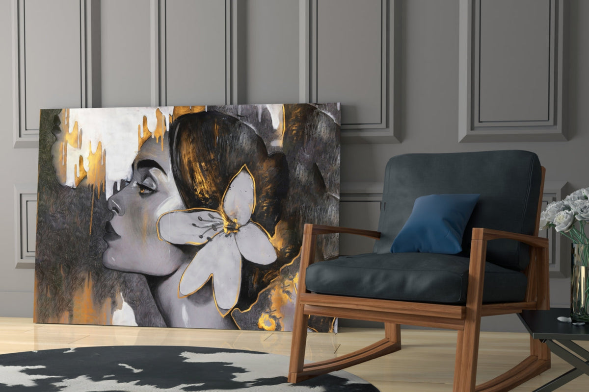 Woman with a white lily in gold and gray glass wall art beside a rocking armchair against gray paneling