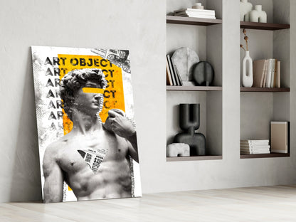 Marble statue on yellow newsprint collage glass wall art leaning against a white wall beside open shelves with vases