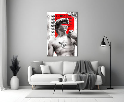 Marble statue on red newsprint collage glass wall art above a light gray sofa with a gray throw and a black floor lamp