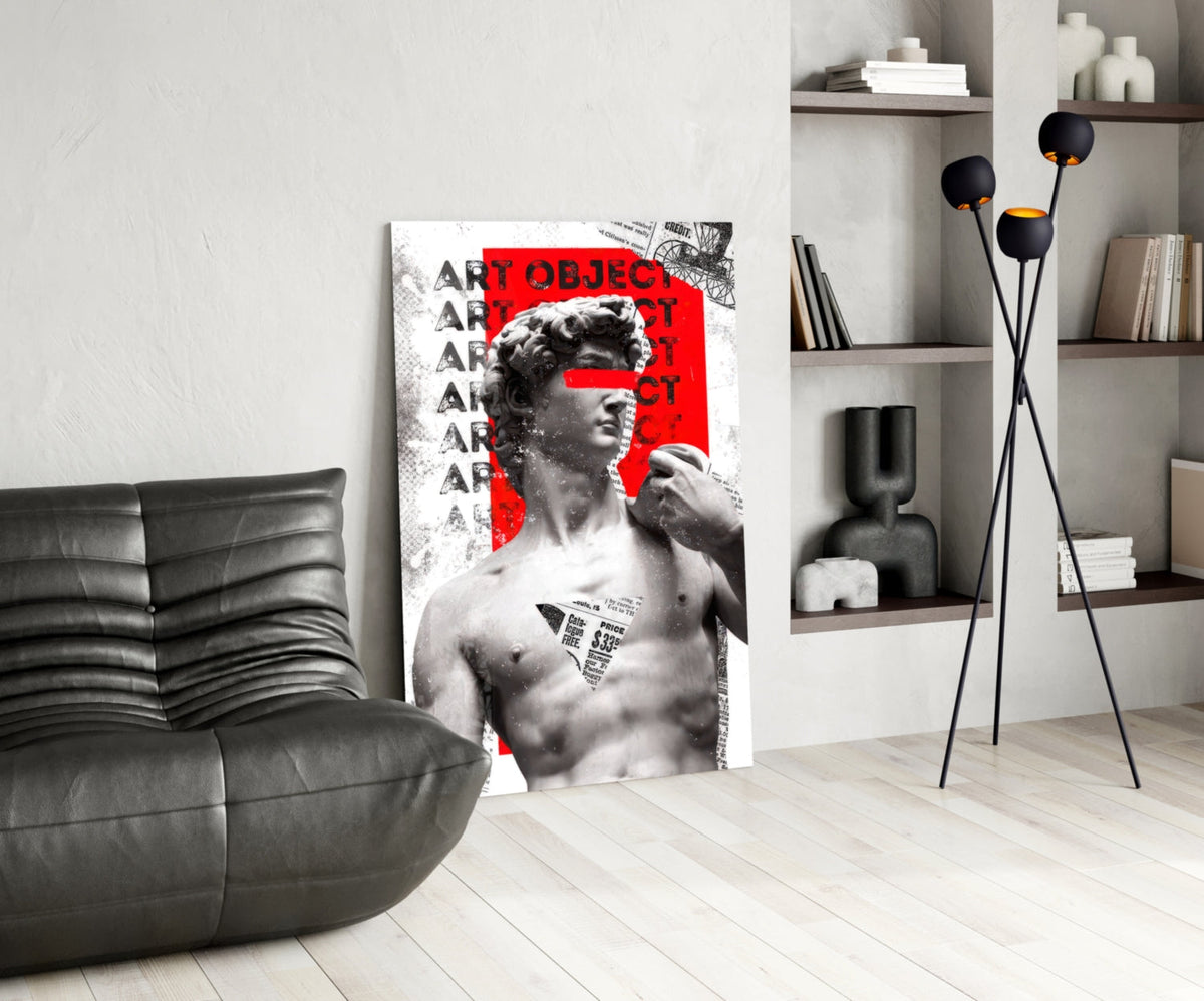 Marble statue on red newsprint collage glass wall art leaning beside a black leather lounge chair and open shelves