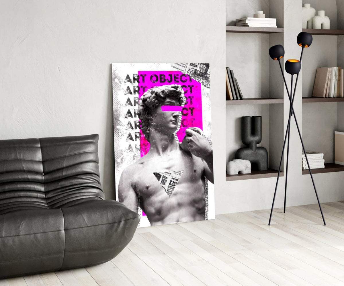 Marble statue on magenta newsprint collage glass wall art leaning beside a black leather lounge chair and open shelves