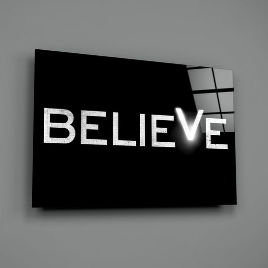 Believe on black with a glowing V glass wall art on a gray wall with a soft shadow