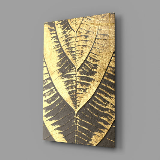 Golden fern leaf on charcoal glass wall art on a gray wall with light reflecting off the glossy front