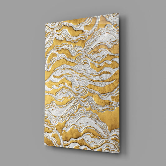Gold and ivory abstract waves glass wall art on a gray wall with light reflecting off the glossy front