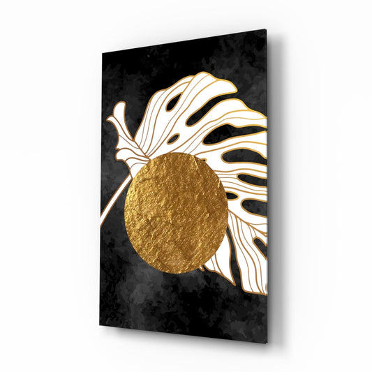 White monstera leaf with gold lines over a centered gold circle on a black background, printed on glass, angled view