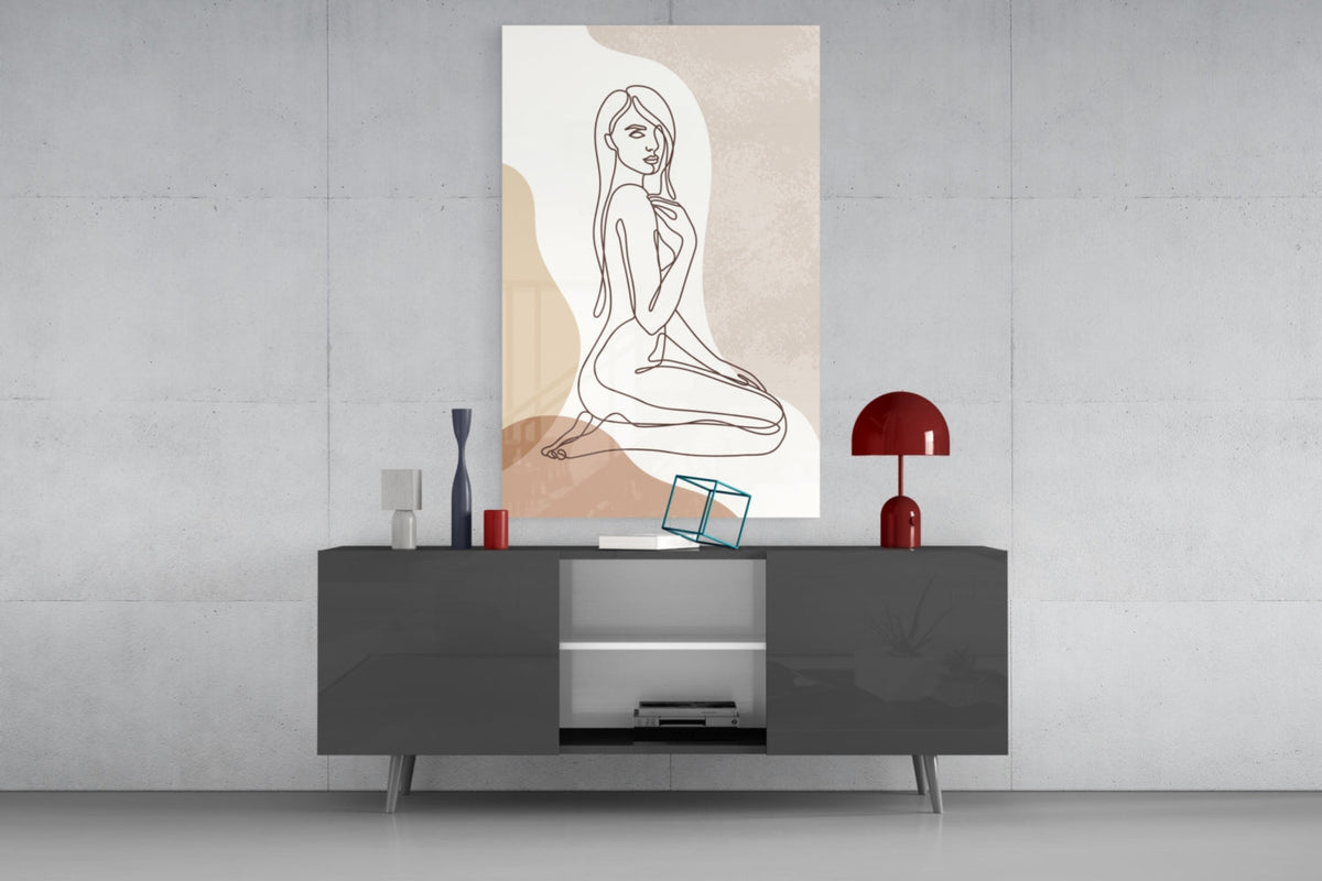 Kneeling woman line art glass wall art above a dark gray media console with a red lamp