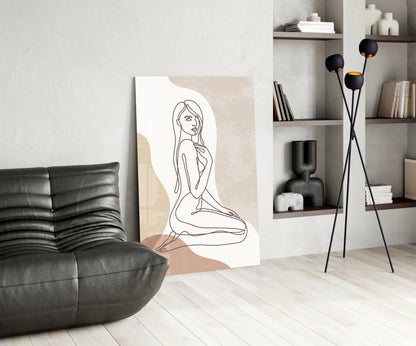 Kneeling woman line art glass print leaning beside a black leather lounge chair and shelves
