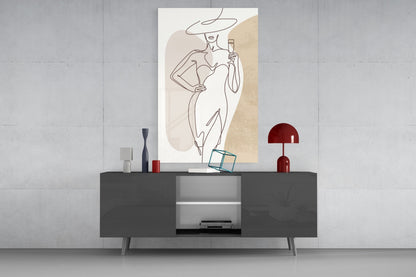 Wide hat line art woman glass wall art above a gray sideboard with a red table lamp