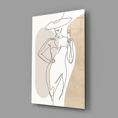 Wide hat line art woman glass wall art hanging on a plain gray wall