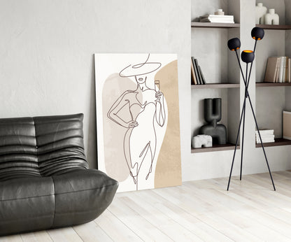Wide hat line art woman glass wall art leaning on a wall beside a black leather lounge chair and shelves