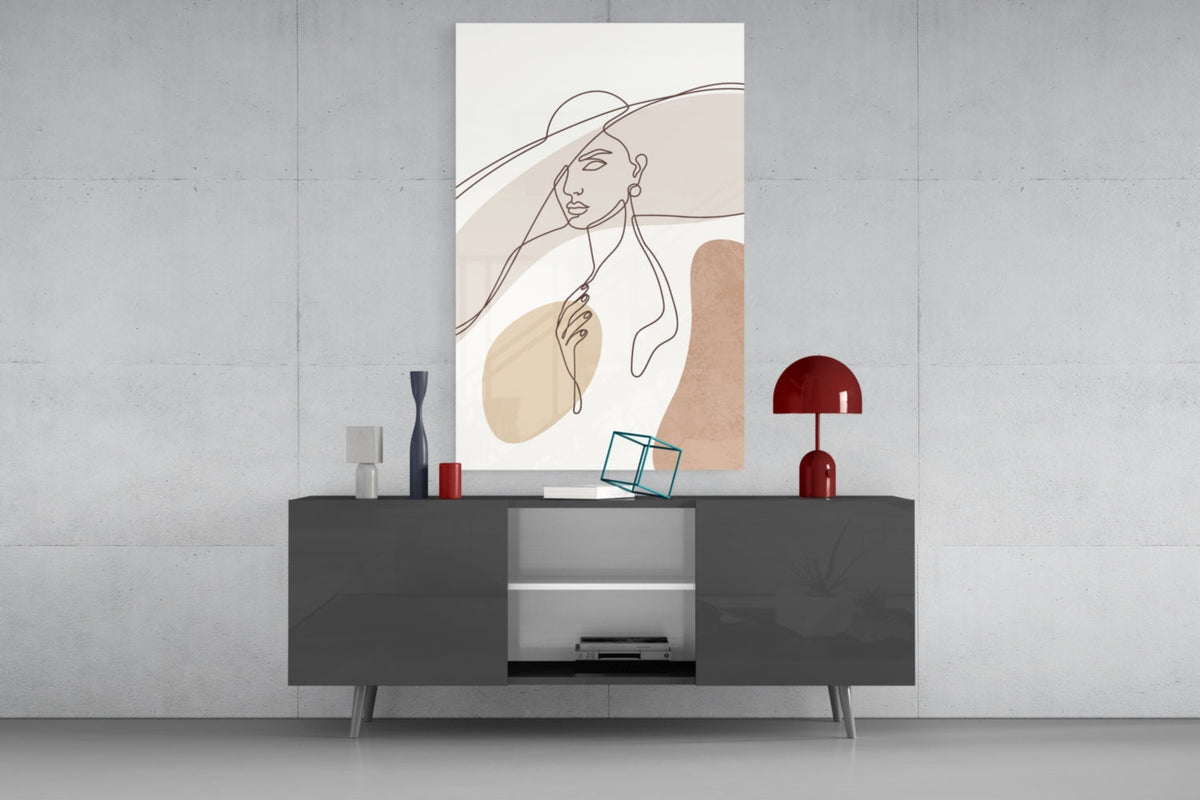 Sun hat line art woman glass wall art above a gray sideboard with a red table lamp