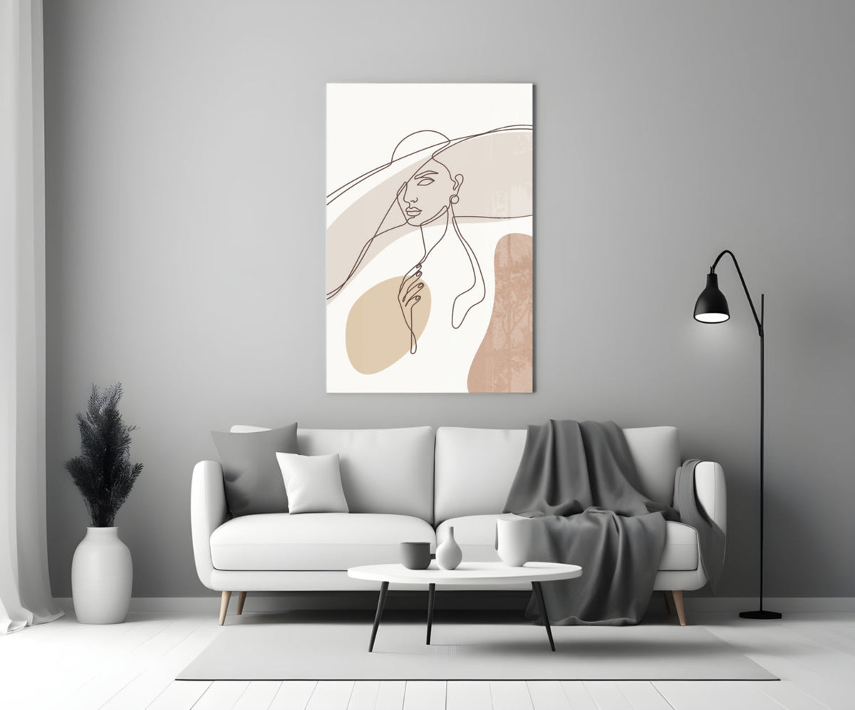Sun hat line art woman glass wall art above a white sofa with a gray throw and a black floor lamp