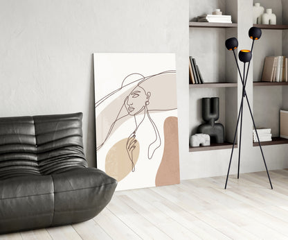 Sun hat line art woman glass wall art leaning on a wall beside a black leather lounge chair and shelves