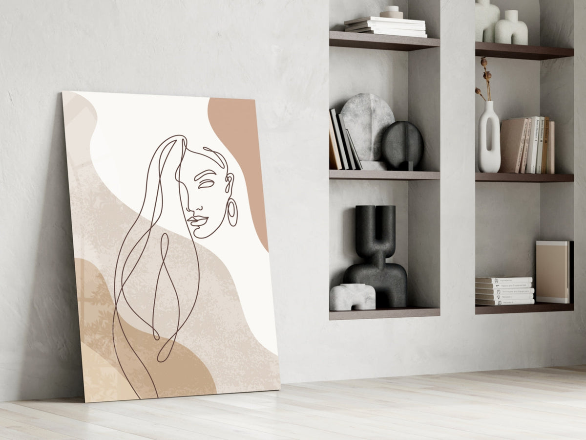 Line art woman with flowing hair glass wall art leaning against a white wall beside open shelves