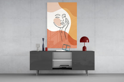 Terracotta line art face glass wall art above a dark gray media console with a red lamp