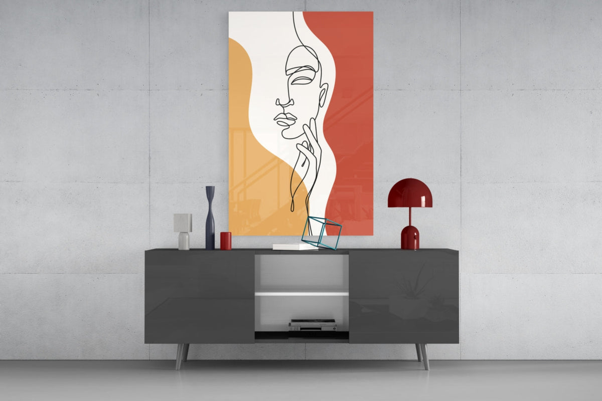 Rust line art face glass wall art above a dark gray media console with a red lamp