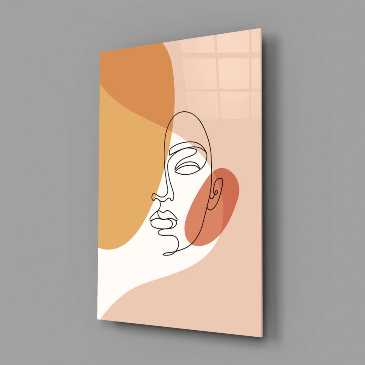 Peach line art face glass wall art hanging on a plain gray wall
