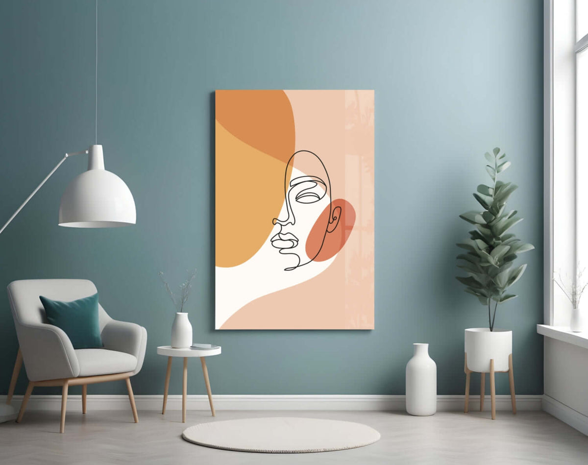 Peach line art face glass wall art on a teal wall beside a white armchair and a white pendant lamp