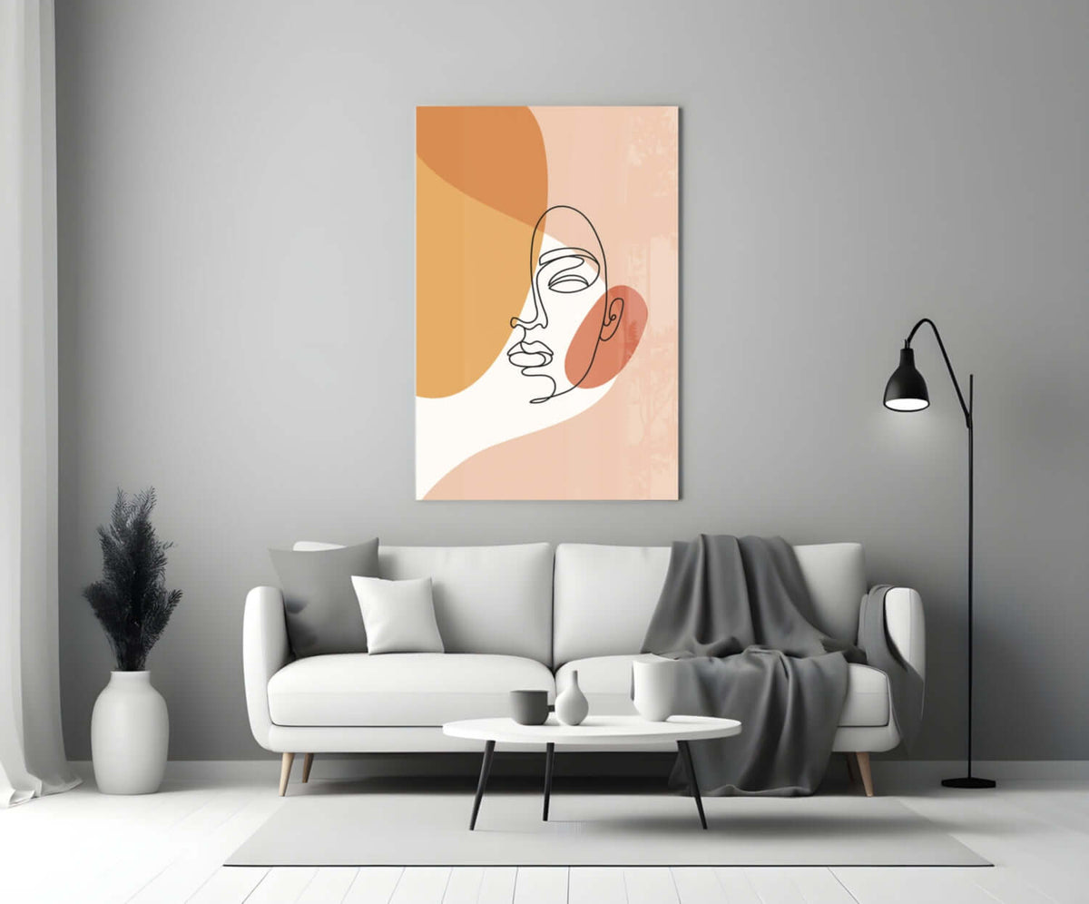 Peach line art face glass wall art above a white sofa with a gray throw and a black floor lamp