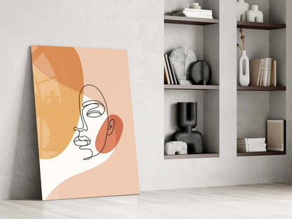 Peach line art face glass wall art leaning beside built-in shelves with vases and books