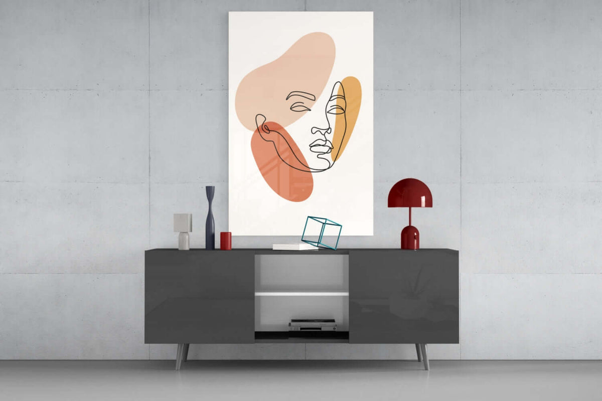 Line art woman face glass wall art above a dark gray media console with a red table lamp