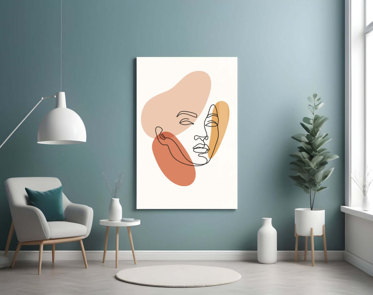 Line art woman face glass wall art on a teal wall above a gray armchair and a white pendant lamp