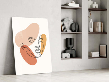 Line art woman face glass wall art leaning against a white wall beside open shelves